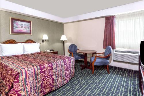 a hotel room with a bed and a table and chairs at Days Inn by Wyndham Dumfries Quantico in Dumfries