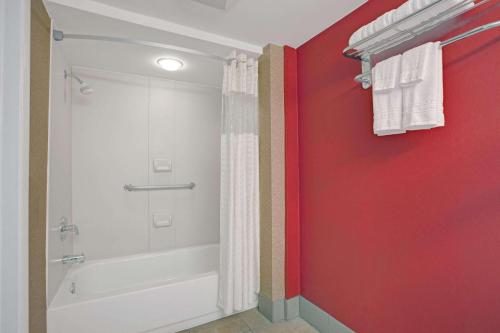 ein Badezimmer mit einer weißen Badewanne und einer roten Wand in der Unterkunft Days Inn by Wyndham Ridgefield NJ in Ridgefield