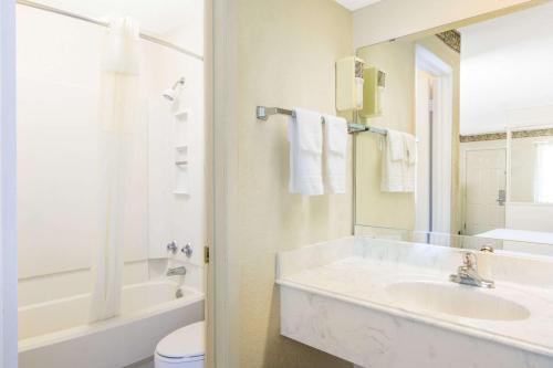 ein Badezimmer mit einer Badewanne, einem Waschbecken und einem WC in der Unterkunft Days Inn & Suites by Wyndham Marshall in Marshall