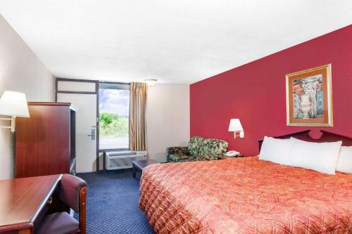 a hotel room with a bed with a red wall at Days Inn by Wyndham Martin in Martin
