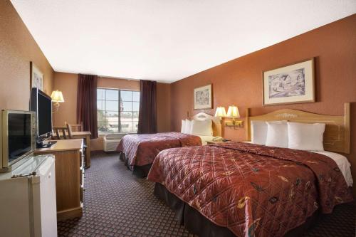 um quarto de hotel com duas camas e uma televisão de ecrã plano em Days Inn & Suites by Wyndham Surprise em Surprise