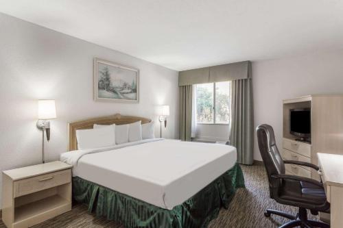 um quarto de hotel com uma cama grande e uma secretária em Days Hotel by Wyndham Peoria Glendale Area em Peoria