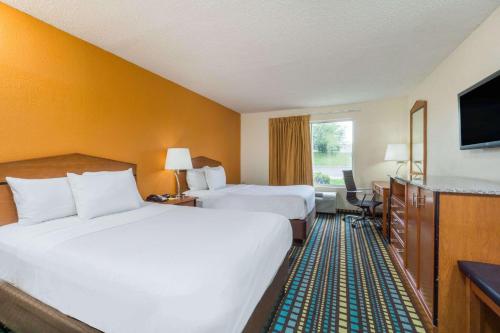 a hotel room with two beds and a television at Days Inn by Wyndham Florence Cincinnati Area in Florence