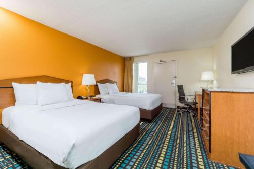 a hotel room with two beds and a flat screen tv at Days Inn by Wyndham Florence Cincinnati Area in Florence