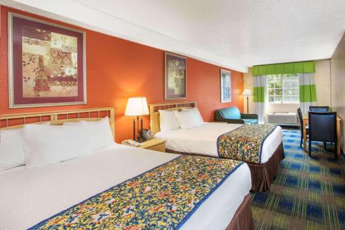 a hotel room with two beds and a desk at Days Inn by Wyndham Fremont in Fremont