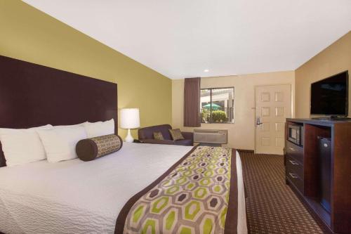 a hotel room with a bed and a flat screen tv at Days Inn by Wyndham San Jose Airport in Milpitas