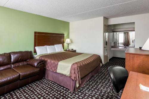 a hotel room with a bed and a leather couch at Days Inn by Wyndham Midland in Midland