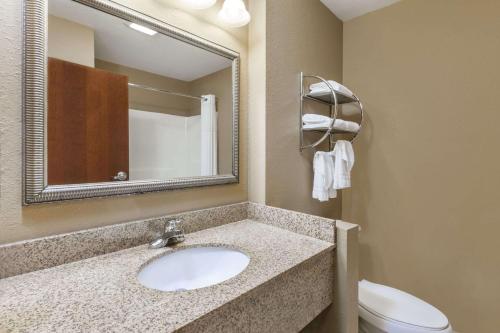 a bathroom with a sink and a toilet and a mirror at Days Inn by Wyndham Central City in Central City