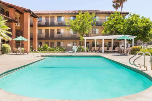 a swimming pool in front of a hotel with a building at Days Inn by Wyndham San Jose Airport in Milpitas