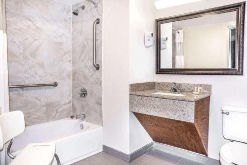 a bathroom with a tub and a sink and a mirror at Days Inn by Wyndham Houston in Houston