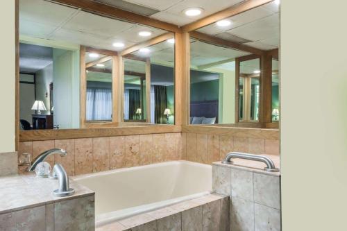 a bath tub in a bathroom with mirrors at Days Inn by Wyndham Midland in Midland