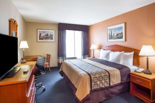 Habitación de hotel con cama, escritorio y TV. en Days Inn & Suites by Wyndham Thibodaux, en Thibodaux