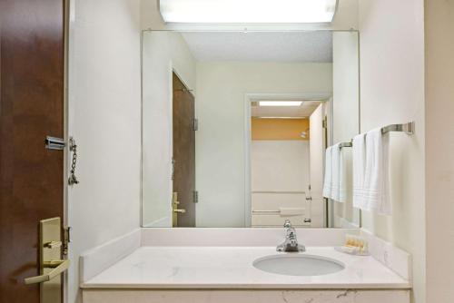 La salle de bains est pourvue d'un lavabo et d'un grand miroir. dans l'établissement Days Inn by Wyndham Burlington East, à Haw River