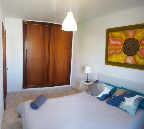 a bedroom with a white bed and a painting on the wall at El Hierro in El Médano