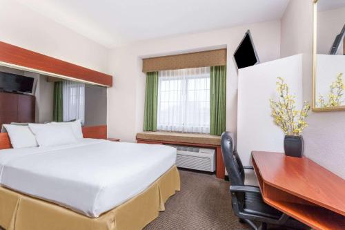 a hotel room with a bed and a desk at Days Inn by Wyndham near Kansas Speedway in Kansas City