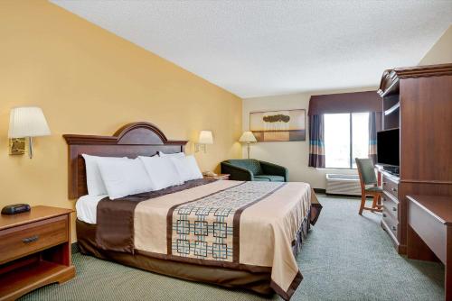 a hotel room with a bed and a television at Days Inn by Wyndham Burlington East in Haw River
