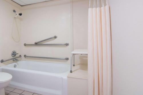 a bathroom with a bath tub and a toilet at Days Inn by Wyndham N.W. Medical Center in San Antonio