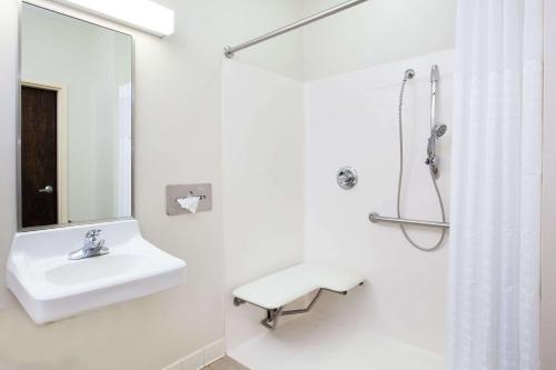 een witte badkamer met een wastafel en een douche bij Days Inn by Wyndham Brewerton/ Syracuse near Oneida Lake in Brewerton