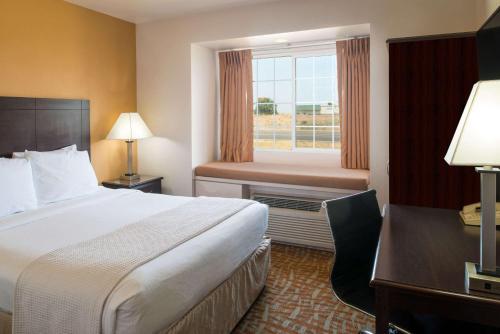 a hotel room with a bed and a desk and a window at Days Inn & Suites by Wyndham Spokane Airport Airway Heights in Airway Heights