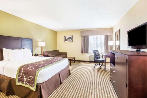 a hotel room with a bed and a flat screen tv at Days Inn by Wyndham Brewerton/ Syracuse near Oneida Lake in Brewerton