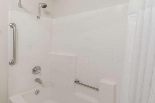 a white bathroom with a shower and a tub at Hospitality Inn in San Bernardino
