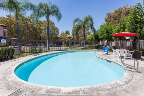 a pool with an umbrella and a table and chairs at Hospitality Inn in San Bernardino