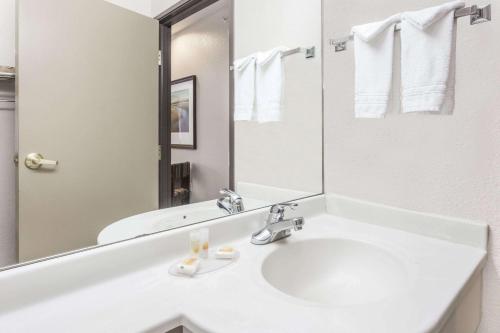 een witte badkamer met een wastafel en een spiegel bij Days Inn by Wyndham near Kansas Speedway in Kansas City