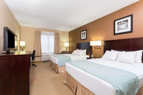 a hotel room with two beds and a flat screen tv at Palm Coast Hotel & Suites-I-95 in Palm Coast
