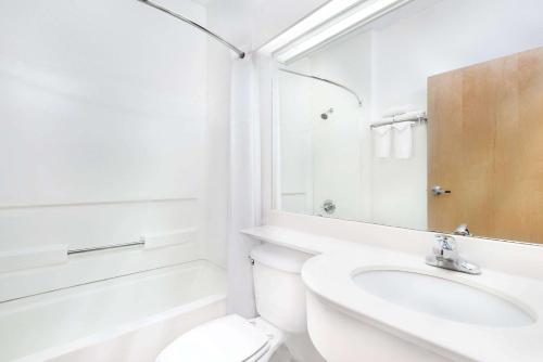 La salle de bains blanche est pourvue de toilettes et d'un lavabo. dans l'établissement Days Inn & Suites by Wyndham Hutchinson, à Hutchinson