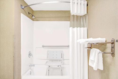 a bathroom with a shower with a white shower curtain at Days Inn by Wyndham Louisburg in Louisburg