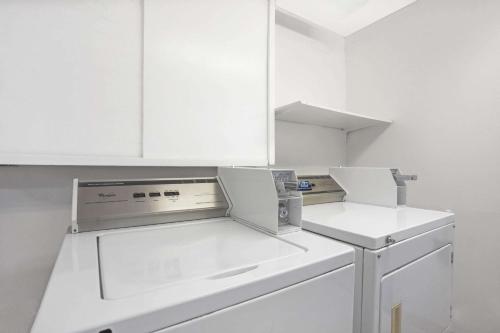 a white kitchen with white cabinets and a dishwasher at Days Inn by Wyndham Seattle North of Downtown in Seattle