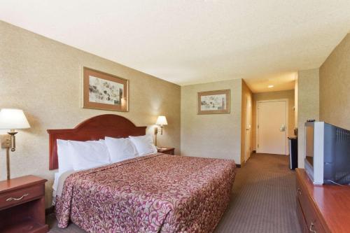 a hotel room with a bed and a flat screen tv at Days Inn & Suites by Wyndham Wynne in Wynne
