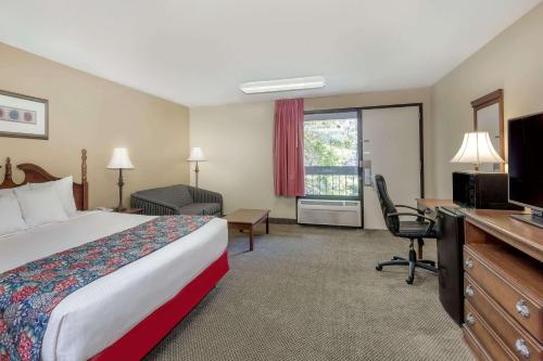 a hotel room with a bed and a desk and a television at Days Inn by Wyndham Hoover Birmingham in Hoover