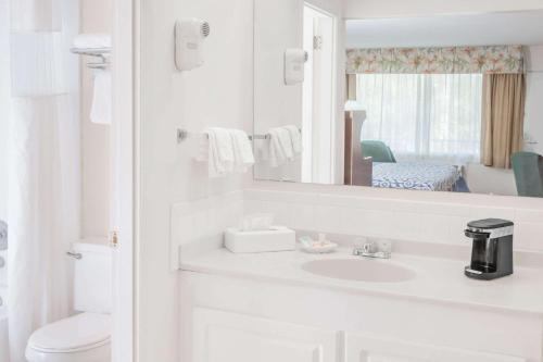Baño blanco con lavabo y espejo en Days Inn by Wyndham Fort Myers Springs Resort, en Estero