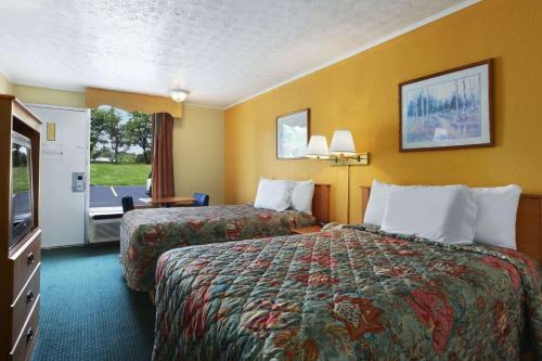 a hotel room with two beds and a television at Days Inn by Wyndham Knoxville West in Knoxville