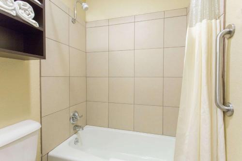 Days Inn & Suites by Wyndham Waterloo في واترلو: حمام مع حوض استحمام أبيض وستارة دش