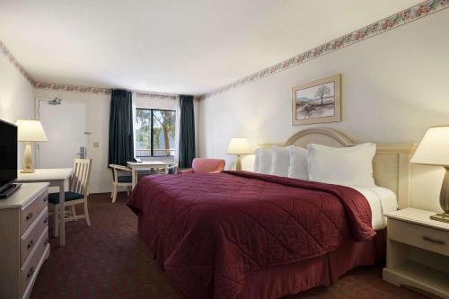 a hotel room with a large bed and a desk at Days Inn by Wyndham Gilroy in Gilroy