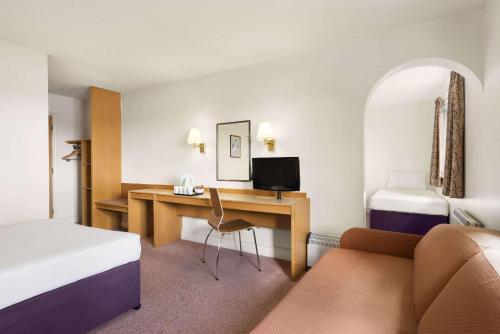 um quarto de hotel com uma secretária e uma cama em Days Inn Kendal - Killington Lake em Kendal