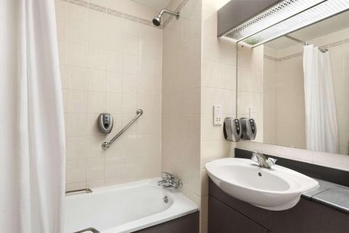 a bathroom with a sink and a tub and a mirror at Days Inn Stafford in Stafford