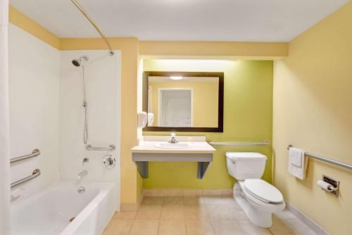 a bathroom with a white toilet and a sink at Days Inn & Suites by Wyndham DeSoto in DeSoto