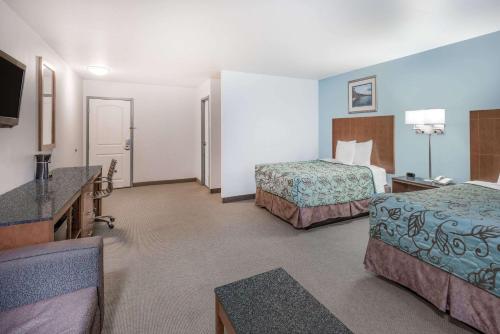 a hotel room with two beds and a flat screen tv at Days Inn by Wyndham Watertown Fort Drum in Evans Mills