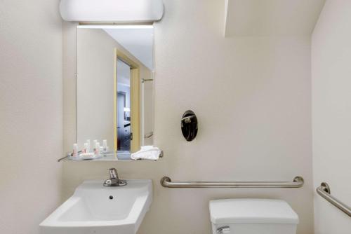 a bathroom with a sink and a toilet and a mirror at Days Inn by Wyndham Geneva/Finger Lakes in Geneva