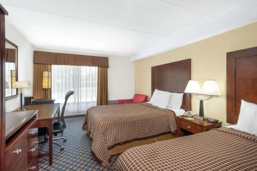 a hotel room with two beds and a desk at Days Inn by Wyndham Geneva/Finger Lakes in Geneva