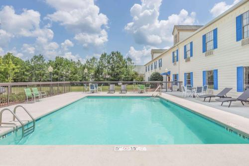 a swimming pool with patio furniture and a building at Days Inn by Wyndham Shallotte in Shallotte