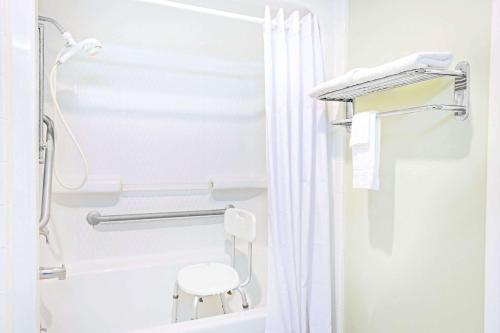 a white bathroom with a shower and a white stool at Days Inn by Wyndham Kingsland GA in Kingsland