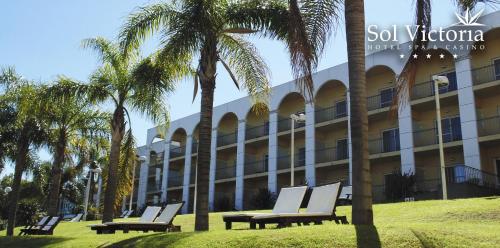 a hotel with palm trees and lounge chairs in front of it at Sol Victoria Hotel SPA & Casino in Victoria
