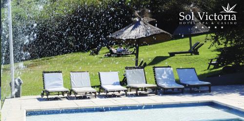 a group of chairs sitting next to a swimming pool at Sol Victoria Hotel SPA & Casino in Victoria