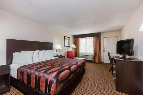 a hotel room with a bed and a flat screen tv at Days Inn by Wyndham Pearl/Jackson Airport in Pearl