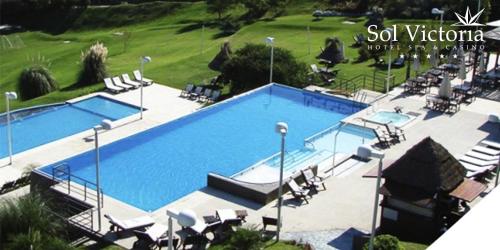 a large swimming pool with lounge chairs at Sol Victoria Hotel SPA & Casino in Victoria