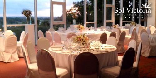 a room filled with tables and chairs with white tables and white chairs at Sol Victoria Hotel SPA & Casino in Victoria